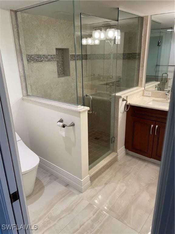 bathroom featuring a stall shower, toilet, vanity, and baseboards