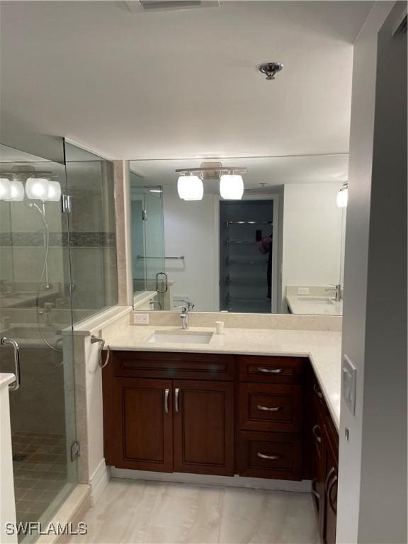 bathroom featuring a shower stall, vanity, and a spacious closet