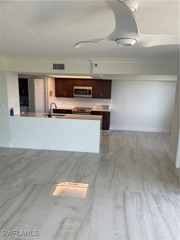kitchen with appliances with stainless steel finishes, a sink, ornamental molding, light marble finish floors, and a peninsula