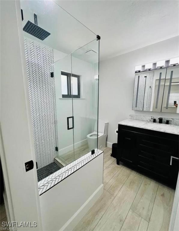 3650 1st Ave SW, Naples, FL 34117 - full bathroom featuring a stall shower, vanity, toilet, and wood finished floors