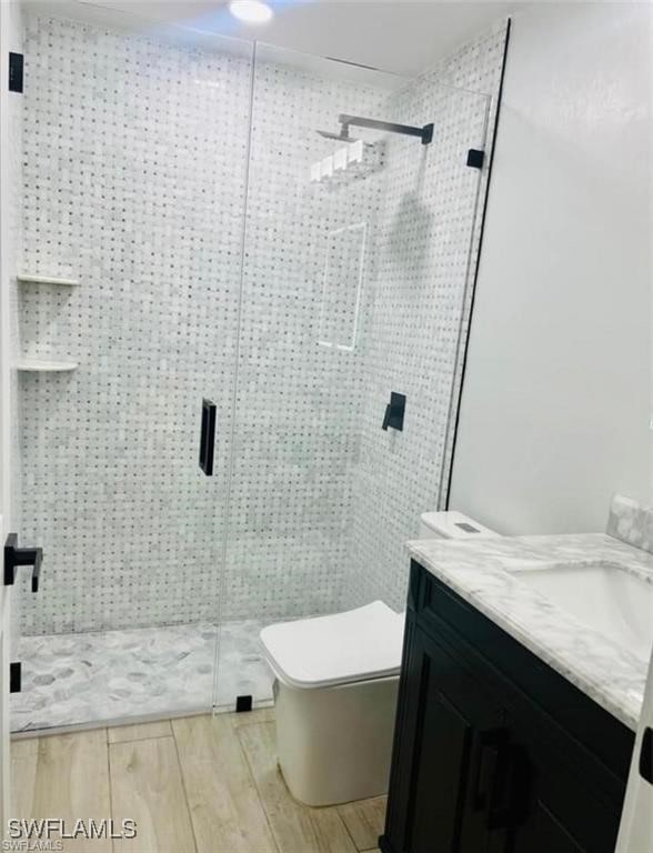 3650 1st Ave SW, Naples, FL 34117 - bathroom with vanity, toilet, a shower stall, and wood finished floors
