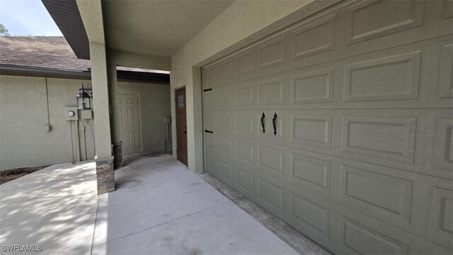 7311 Sean Ln, North Fort Myers, FL 33917 - property entrance featuring a garage, roof with shingles, and stucco siding