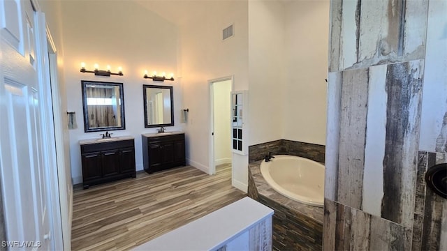 7311 Sean Ln, North Fort Myers, FL 33917 - full bathroom featuring a garden tub, double vanity, a high ceiling, baseboards, and wood finished floors