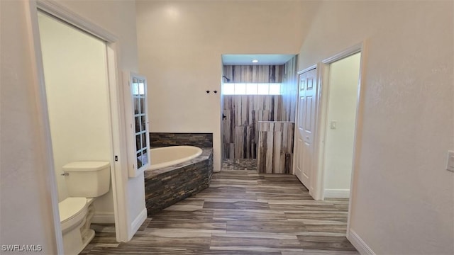 7311 Sean Ln, North Fort Myers, FL 33917 - bathroom with a bath, wood finished floors, toilet, and baseboards