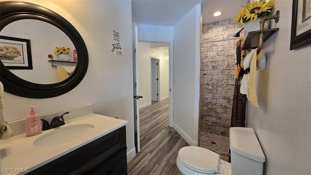 7311 Sean Ln, North Fort Myers, FL 33917 - bathroom with toilet, a tile shower, vanity, wood finished floors, and baseboards