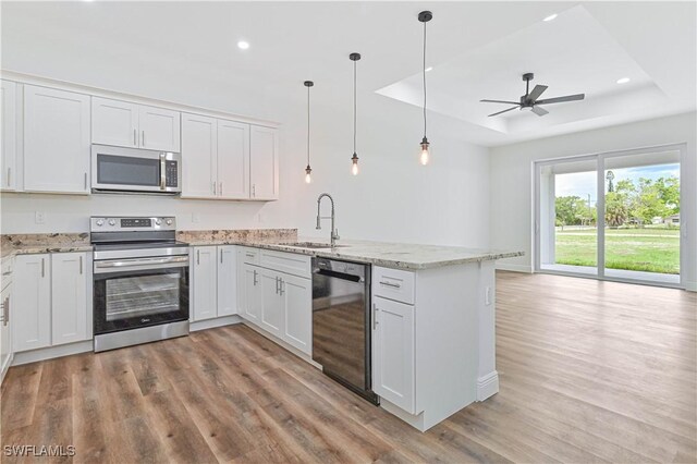 2174 Highland Ave, Fort Myers, FL 33916 - kitchen with appliances with stainless steel finishes, a raised ceiling, a sink, a peninsula, and light wood-style flooring