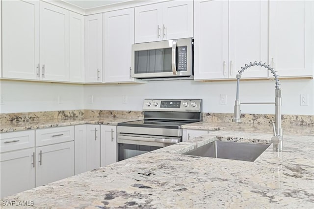 2174 Highland Ave, Fort Myers, FL 33916 - kitchen with appliances with stainless steel finishes, a sink, white cabinets, and light stone counters