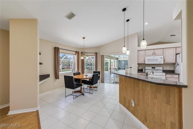 6731 Blake Pledger Ct, North Fort Myers, FL 33917 - kitchen featuring hanging light fixtures, range, vaulted ceiling, white microwave, and visible vents