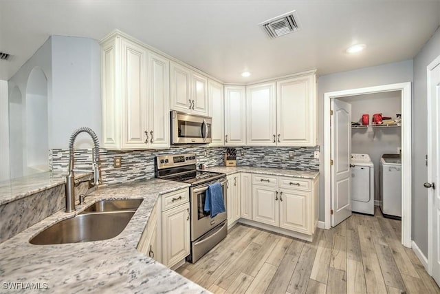 1137 Nelson Rd N, Cape Coral, FL 33993 - kitchen with independent washer and dryer, appliances with stainless steel finishes, a sink, light wood-style floors, and visible vents