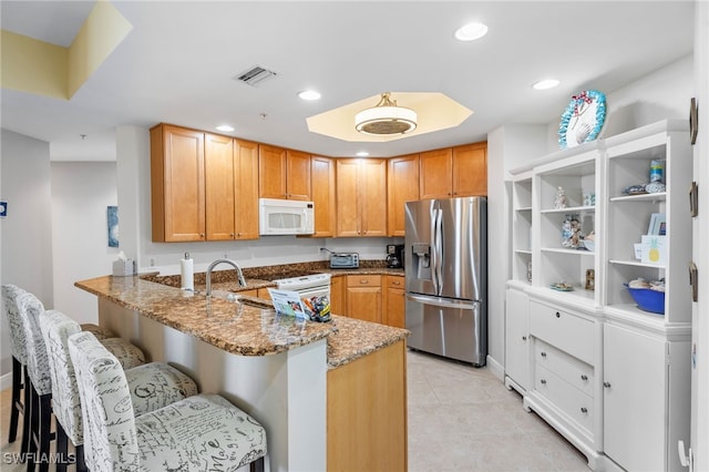 5781 Cape Harbour Dr Unit 610, Cape Coral, FL 33914 - kitchen with a peninsula, white microwave, stainless steel refrigerator with ice dispenser, visible vents, and light stone countertops