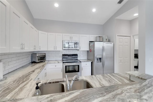 14831 Blackbird Ln, Fort Myers, FL 33919 - kitchen with stainless steel appliances, light stone counters, white cabinets, backsplash, and recessed lighting