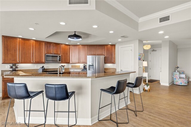 3414 Hancock Bridge Pkwy Unit 502, North Fort Myers, FL 33903 - kitchen featuring stainless steel appliances, a raised ceiling, ornamental molding, brown cabinets, and recessed lighting