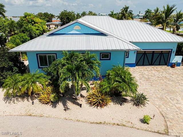 view of front of house with a garage, stucco siding, driveway, and metal roof
