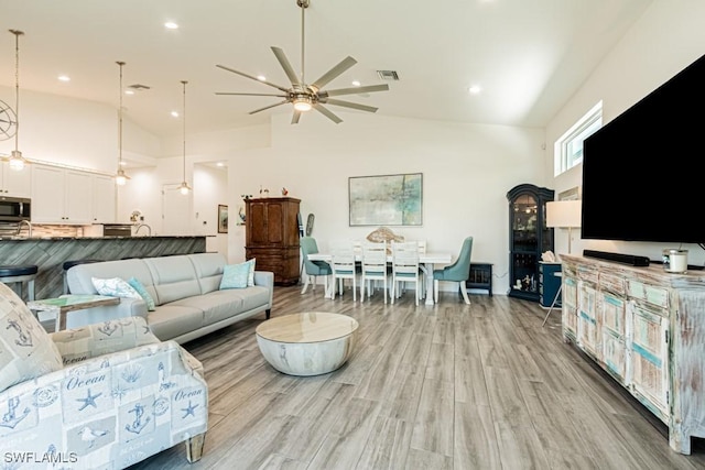 living area featuring light wood-style floors, recessed lighting, ceiling fan, and high vaulted ceiling