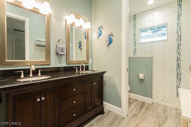 full bathroom featuring toilet, a tile shower, and a sink