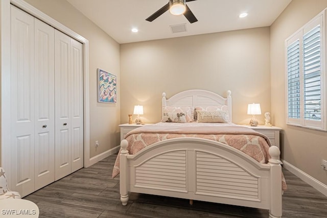 bedroom featuring baseboards, multiple windows, wood finished floors, and a closet
