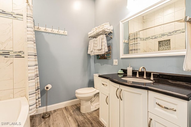 bathroom featuring toilet, baseboards, wood finished floors, and vanity