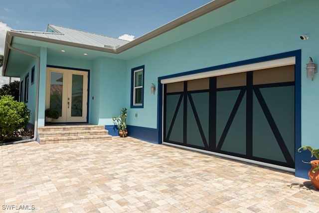 exterior space featuring an attached garage, decorative driveway, and french doors