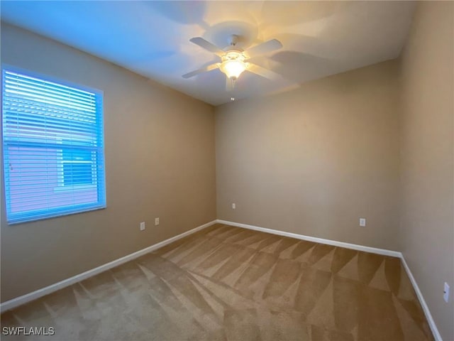 empty room featuring light colored carpet, baseboards, and ceiling fan