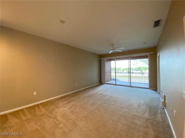 carpeted spare room featuring baseboards and a ceiling fan