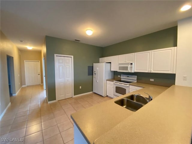 kitchen featuring white appliances, a sink, light tile patterned flooring, white cabinets, and baseboards