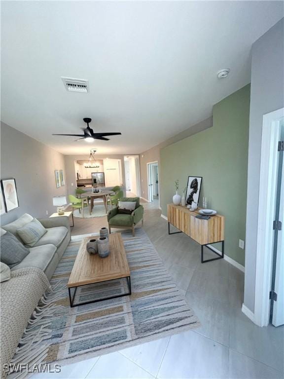 tiled living room featuring a ceiling fan, baseboards, and visible vents