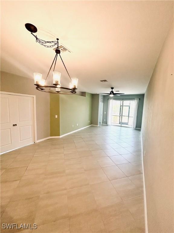unfurnished room featuring light tile patterned flooring, baseboards, visible vents, and ceiling fan with notable chandelier