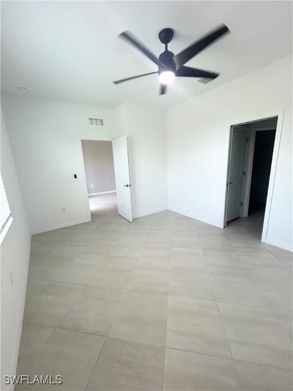 empty room featuring light tile patterned floors, a ceiling fan, and visible vents