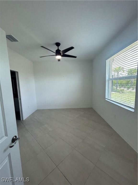 empty room with visible vents, baseboards, ceiling fan, and light tile patterned floors