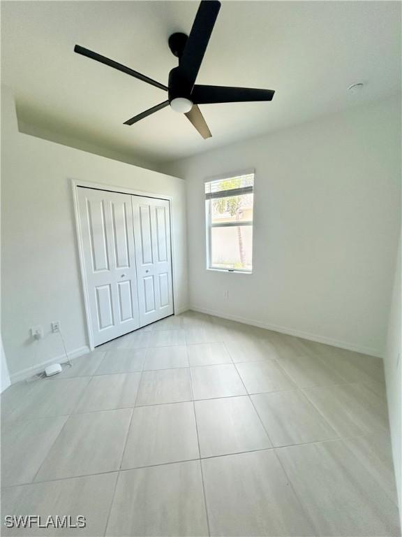 unfurnished bedroom with a ceiling fan, tile patterned floors, baseboards, and a closet