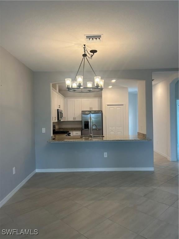 kitchen with an inviting chandelier, a peninsula, baseboards, white cabinetry, and stainless steel appliances