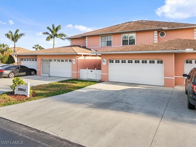 traditional-style house featuring a garage, stucco siding, driveway, and fence