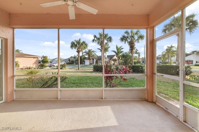unfurnished sunroom featuring a residential view and a ceiling fan