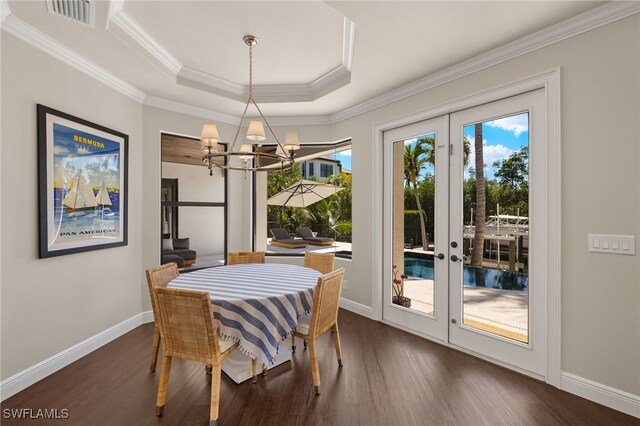 dining area with a tray ceiling, dark wood finished floors, french doors, and visible vents