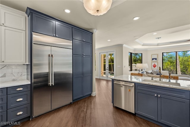 kitchen featuring a sink, open floor plan, dark wood-style flooring, appliances with stainless steel finishes, and ornamental molding