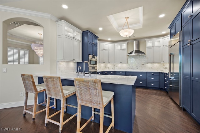 15460 Catalpa Cove Ln, Fort Myers, FL 33908 - kitchen with a tray ceiling, wall chimney range hood, stainless steel appliances, ornamental molding, and dark wood-type flooring