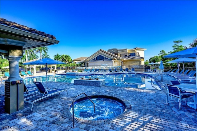 community pool with a hot tub, a patio, and fence