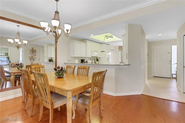 dining area featuring baseboards, a chandelier, ornamental molding, and light wood-style floors