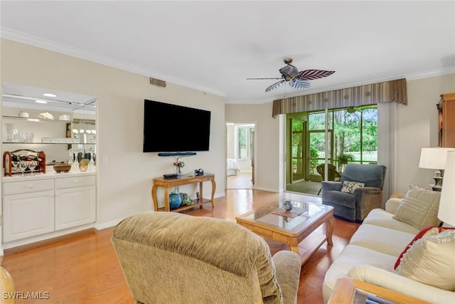 living room featuring ceiling fan, visible vents, ornamental molding, and light wood-type flooring