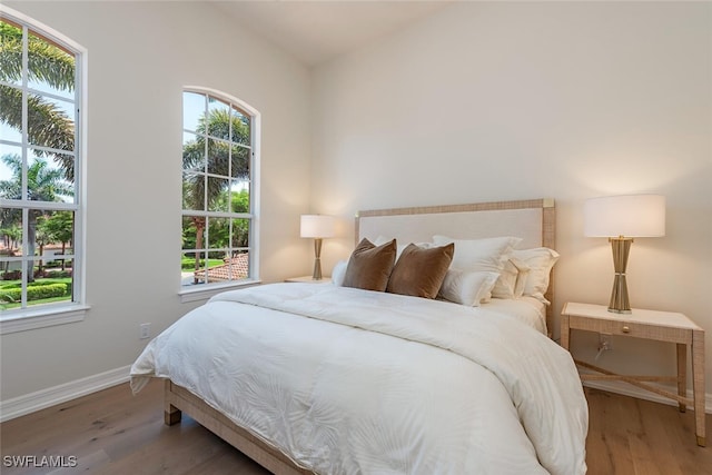 bedroom featuring multiple windows, wood finished floors, and lofted ceiling
