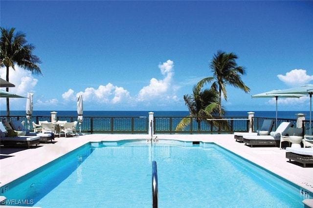 community pool with a patio, a water view, and outdoor lounge area