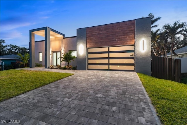 4026 SE 3rd Ave, Cape Coral, FL 33904 - contemporary home featuring a front yard, decorative driveway, fence, an attached garage, and stucco siding