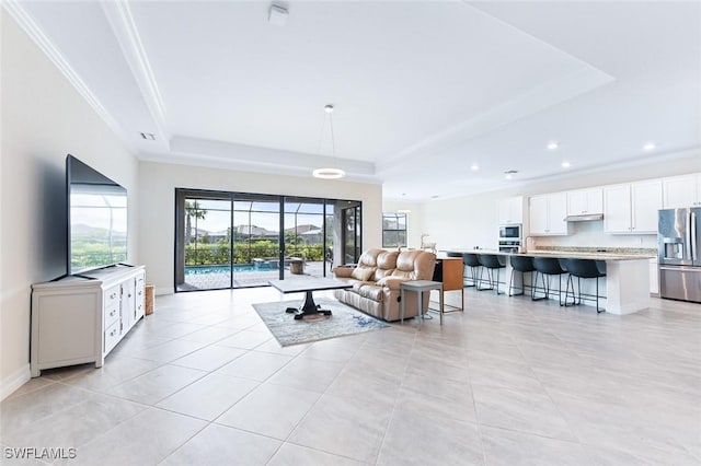 living area featuring plenty of natural light, a raised ceiling, and ornamental molding
