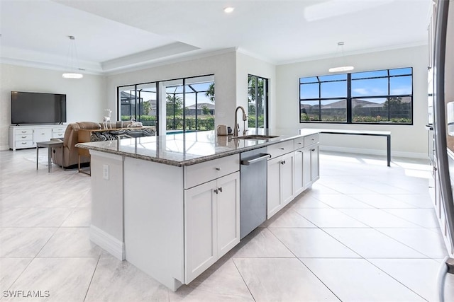 kitchen with a sink, plenty of natural light, stone counters, and an island with sink