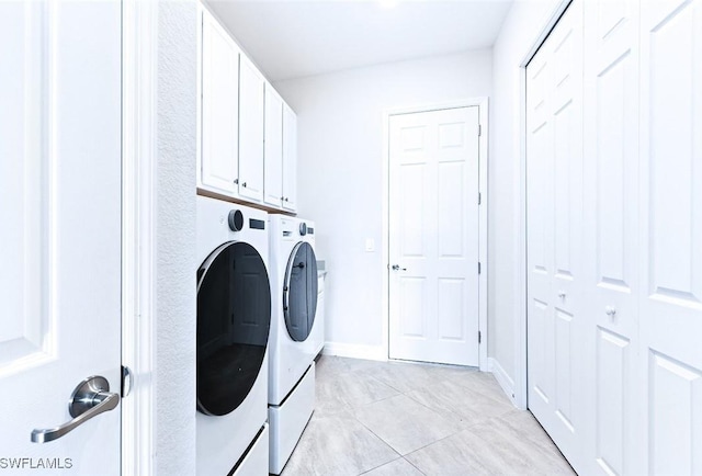 laundry room with light tile patterned floors, baseboards, cabinet space, and washing machine and clothes dryer