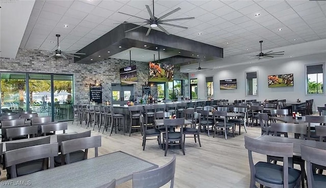dining space featuring ceiling fan, a drop ceiling, wood finished floors, and a high ceiling
