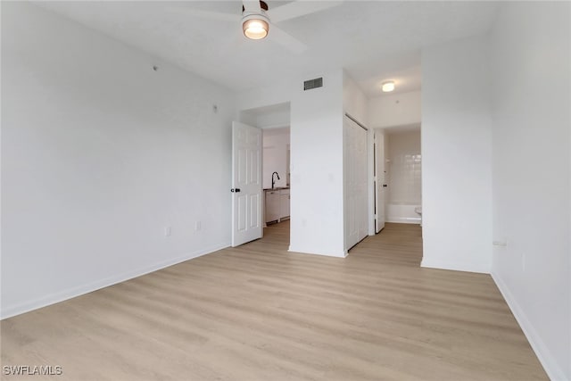 unfurnished bedroom with light wood-type flooring, baseboards, ensuite bathroom, and a sink