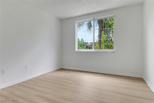 spare room featuring light wood-style floors and baseboards