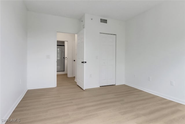 unfurnished bedroom with light wood-style floors, a closet, and baseboards