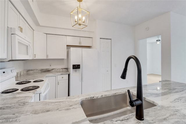 kitchen featuring white appliances, a sink, light stone countertops, white cabinets, and a chandelier